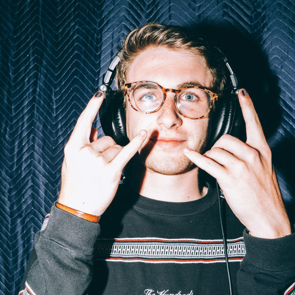 Man with headphones gesturing the devil's horns and wearing Rooted Y nail polish.