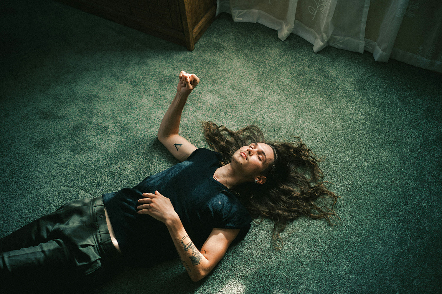 Man laying on hotel room floor wearing XY nail polish