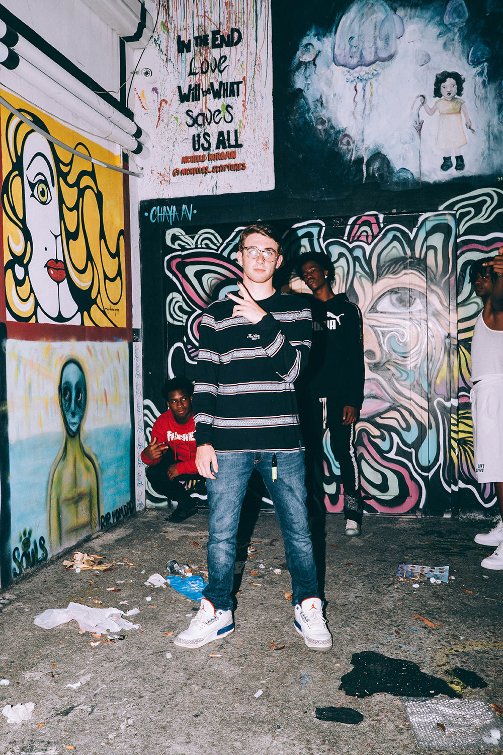 Two men posing in front of graffiti art wearing XY nail polish